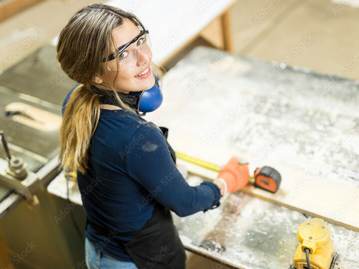 Handwerkerin in Ihrer Werkstatt beim vermessen eines Brettes.